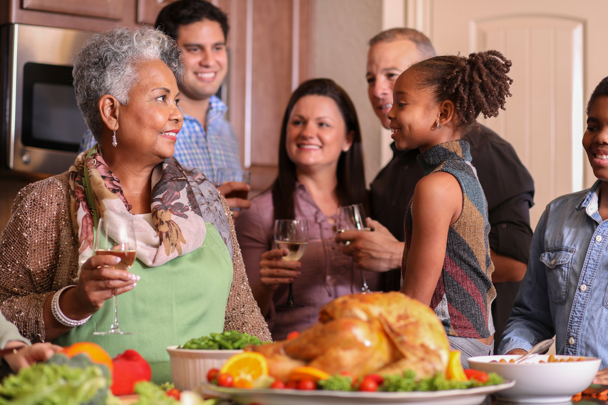 Diverse family in home kitchen cooking Thanksgiving dinner.